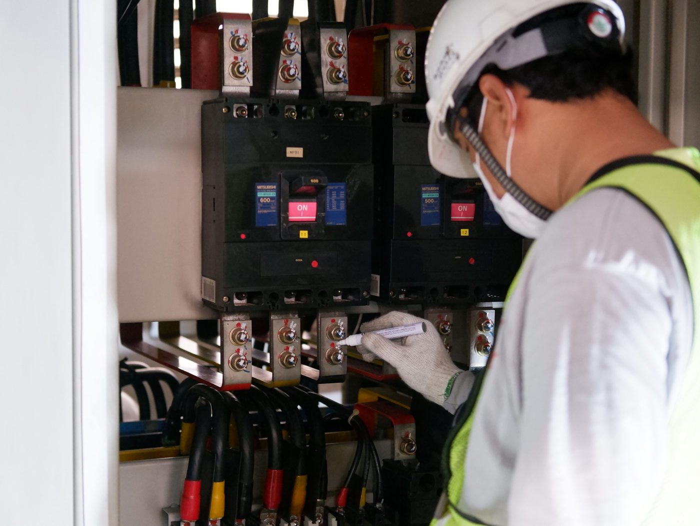 Electrical technician inspecting and marking breaker connections during planned maintenance